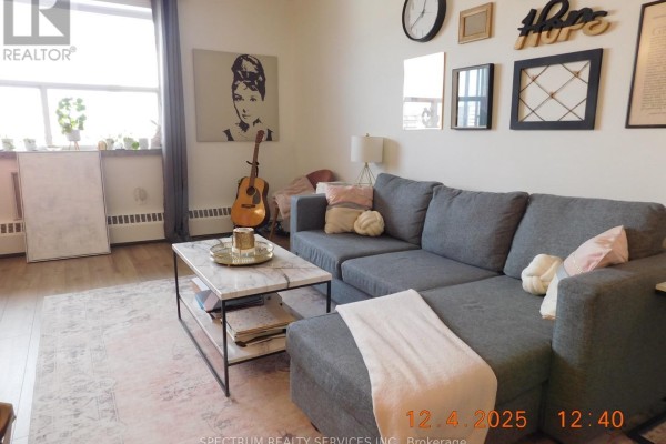 Living room with a grey sectional sofa, marble coffee table, and decorative wall art. - 808 - 3320 Fieldgate Drive, Mississauga