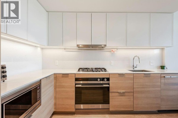 Modern kitchen with white and wood cabinets, stainless steel appliances, and quartz countertops. - 808 1045 Austin Avenue, Coquitlam