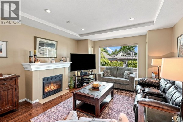 Living room with a fireplace, dark leather sofa, grey sofa, coffee table, and television. - 808 Stanhope Rd, Parksville