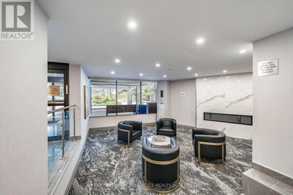 A seating area in the lobby with leather chairs, a coffee table, and a modern fireplace. - 809 - 10 Edgecliffe Golfway, Toronto