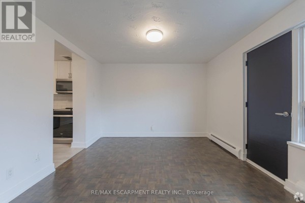 Dining area or flex space with parquet flooring, white walls, and a large dark door. - 809 - 285 Erb Street W, Waterloo