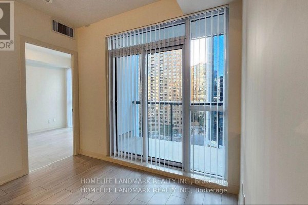 Empty room with light wood floors, large windows, and vertical blinds. - 809 - 4955 Yonge Street, Toronto