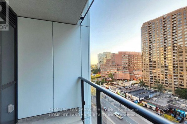 Balcony view with glass railing overlooking a street with buildings and trees. - 809 - 4955 Yonge Street, Toronto