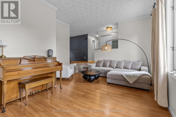 Living room with sectional sofa, piano, coffee table, and a large window with curtains. - 8097 Laurie Lane, Ottawa