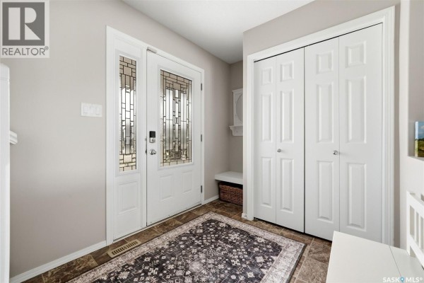 Foyer with a glass-paned front door, tiled floor, and a large white double closet. - 8097 Wascana Gardens Crescent, Regina