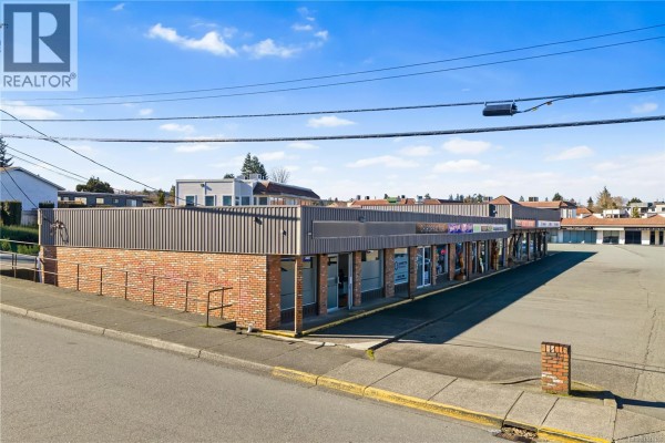 Corner view of a brick and corrugated metal commercial building with glass storefronts and a parking lot. - Unit D 80 Westgate Rd, Campbell River