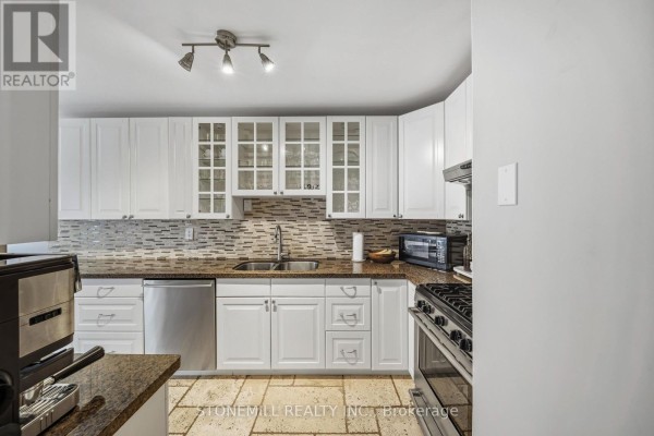 Kitchen with white cabinets, granite countertops, tiled backsplash, stainless steel appliances, and stone tile flooring. - 81 - 2155 South Millway, Mississauga