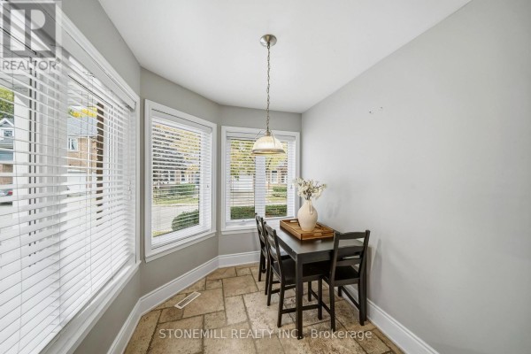 Dining nook with a small dark wood table and chairs by bay windows with white blinds, stone tile floor. - 81 - 2155 South Millway, Mississauga