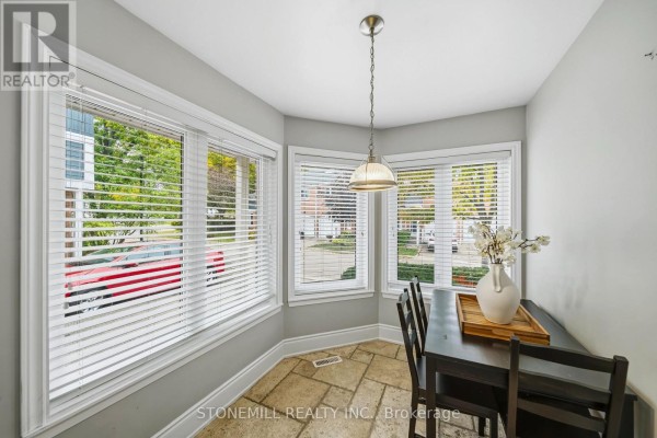 Dining area with a dark wood table and chairs by three large bay windows offering views of the street. - 81 - 2155 South Millway, Mississauga