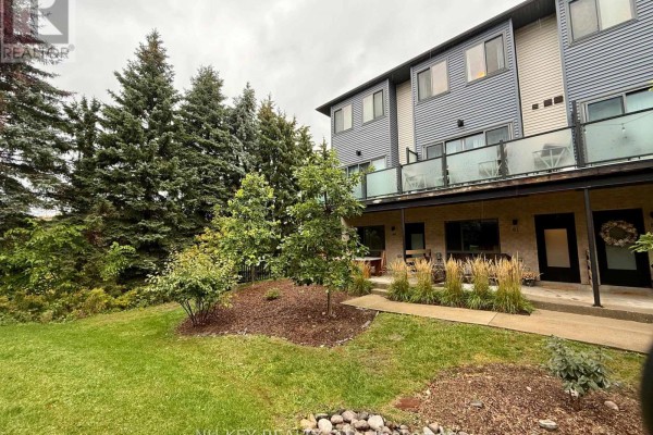 Side view of the townhouse complex with mature trees and lawn. - 81 - 369 Essa Road, Barrie