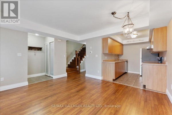 Open concept living space with hardwood floors, kitchen, and staircase visible. - 81 - 4620 Guildwood Way, Mississauga