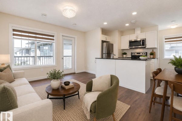 Open-concept living, dining, and kitchen area with a balcony door and large windows. - #81 1530 Tamarack Bv Nw, Edmonton