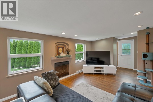 Living room facing opposite direction, showing TV, fireplace, and cat tree with blue accents. - 81 5250 Beaver Harbour Rd, Port Hardy