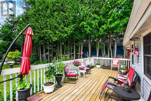 Wooden deck with red patio furniture and potted plants. - 81 Andrew Drive, Tiny