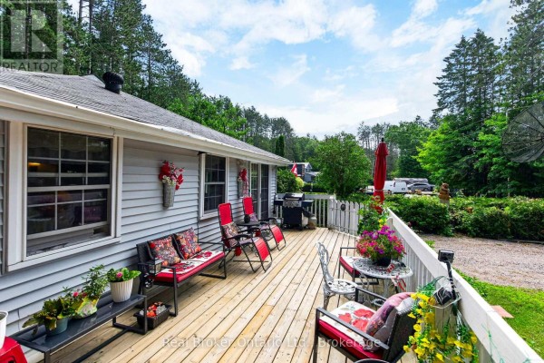 Deck furniture and barbecue visible from the side of the house. - 81 Andrew Drive, Tiny