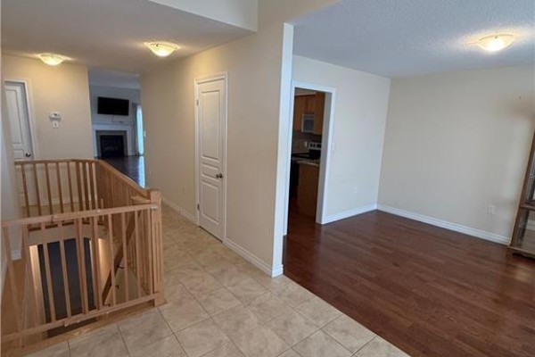 Interior foyer with tiled floor, wood staircase railing, and doorway to living area. - 81 Bellagio Avenue, Hamilton