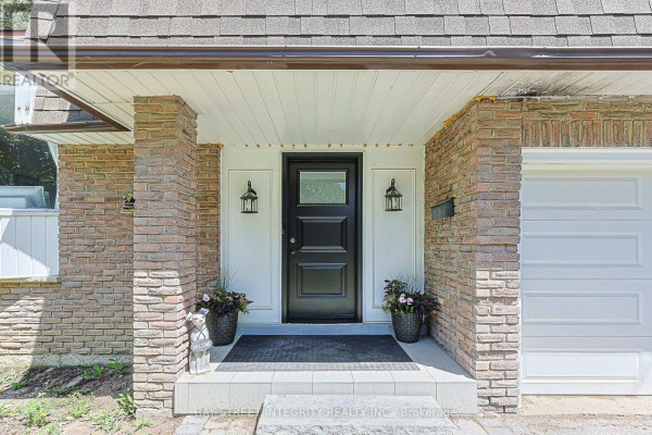 Close-up of the front entrance with a black door, brick accents, and two garage doors. - 81 Dawn Hill Trail, Markham