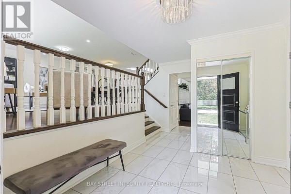 Foyer with white tiled floors, a dark wood staircase, and mirrored closet doors. - 81 Dawn Hill Trail, Markham