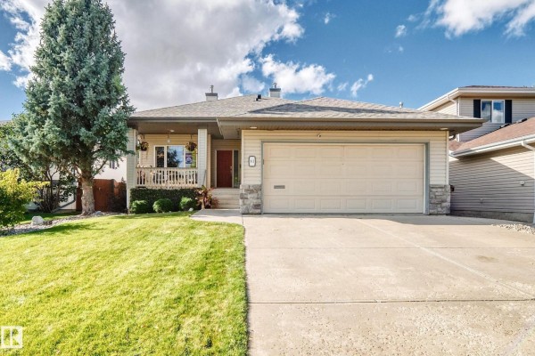 Front exterior view of a light beige vinyl-sided house with a double garage and driveway. - 81 Dunfield Cr, St  Albert