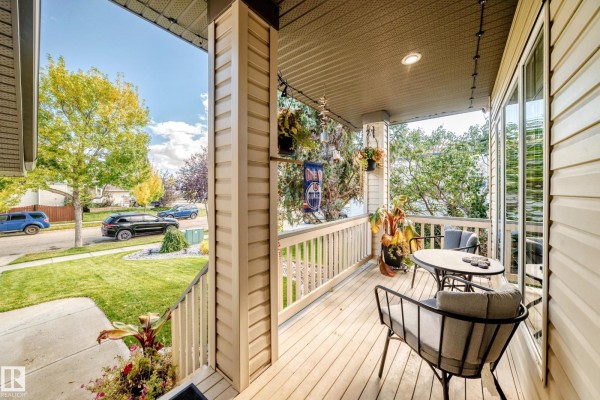 View of a front porch with seating and planters, overlooking a green lawn and street. - 81 Dunfield Cr, St  Albert