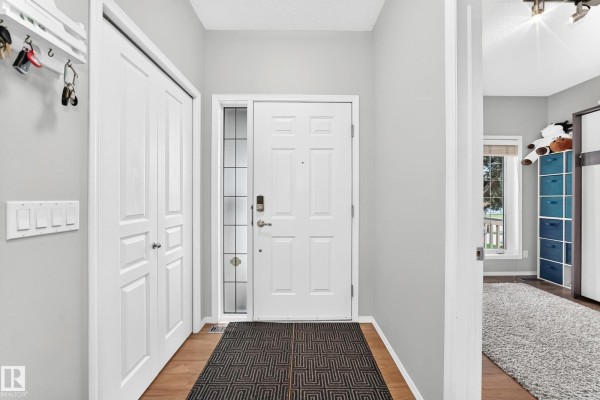 Interior view of a home entrance with a white front door, closet, and wood floors. - 81 Dunfield Cr, St  Albert
