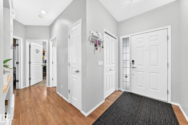 Wide interior view of a home entrance hall with multiple doors, closet, and wood floors. - 81 Dunfield Cr, St  Albert