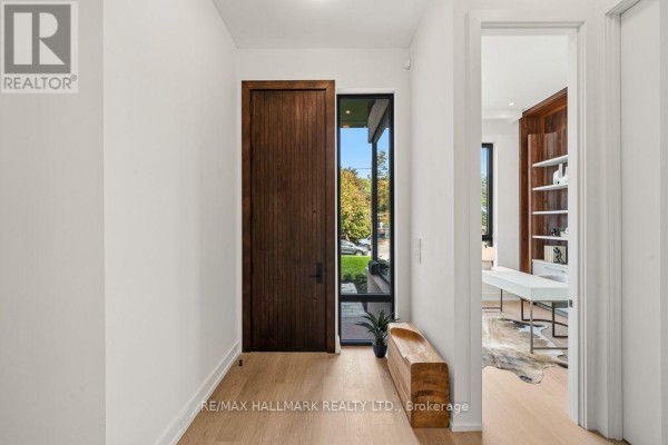 Interior hallway with light wood floors, a large dark wood front door, and view into a home office. - 81 Meadowview Avenue, Markham