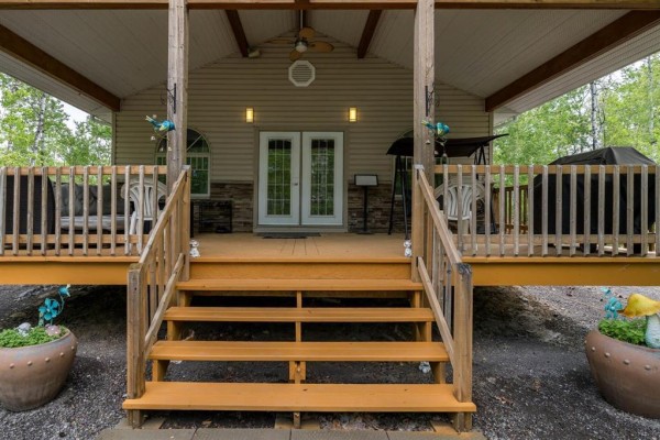 Close-up of the wooden stairs and porch deck leading to the double glass doors of a beige house. - 81 Reisswood Drive, Traverse Bay