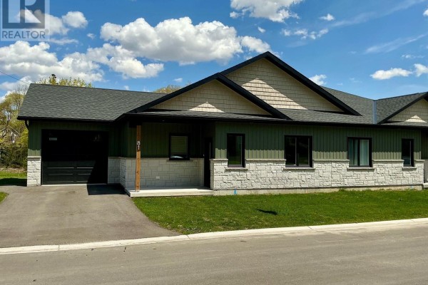 Rear exterior of a green house with a wooden deck overlooking a grassy yard. - 81 Sports Drive, Huron East