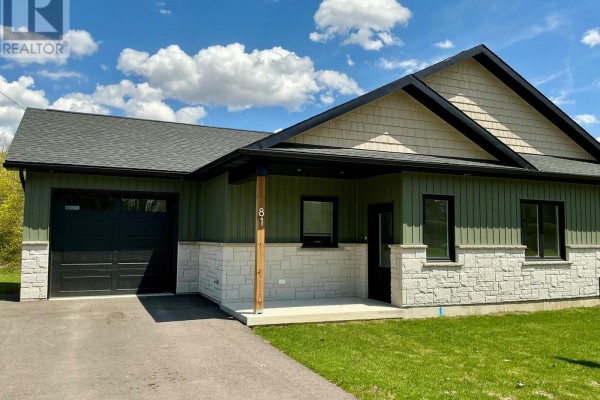 Open-concept kitchen and living area with light wood floors and dark cabinetry. - 81 Sports Drive, Huron East