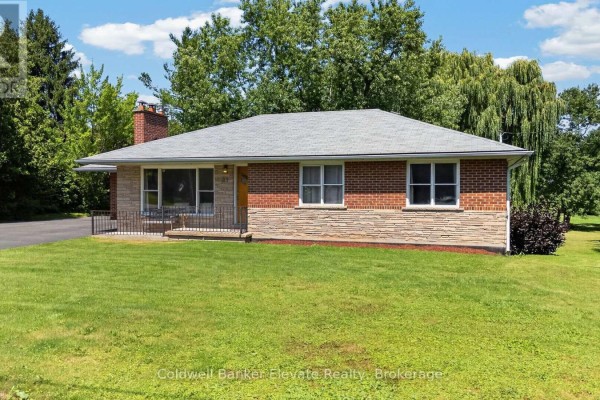 Slightly angled front view of a brick and stone bungalow with a large lawn and mature trees. - 81 Tremaine Road, Milton