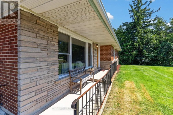 Detail of the front porch of a brick and stone bungalow with a wooden bench and railing. - 81 Tremaine Road, Milton