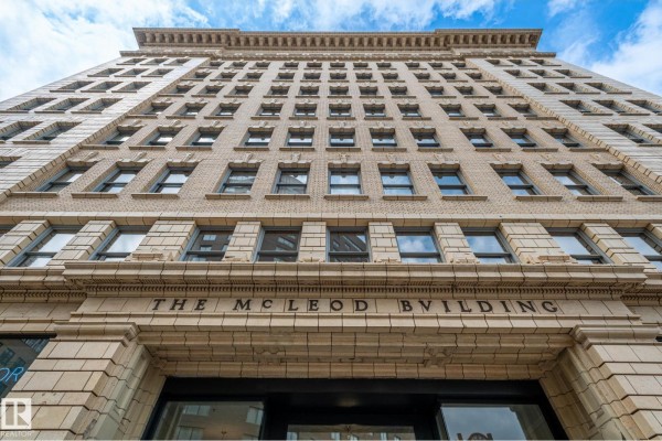 Studio apartment with wood floors, two windows, and a white kitchenette. - #810 10134 100 St Nw, Edmonton