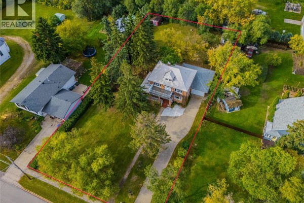 Aerial view showing property lines of a house with a large yard and mature trees. - 810 4th Avenue, Rosthern