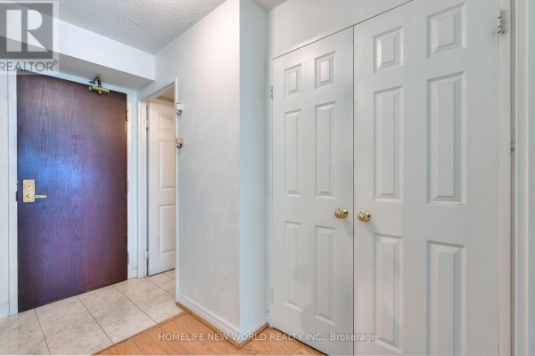 Hallway with a dark wood apartment door, two white closet doors, and beige floor tiles. - 811 - 18 Parkview Avenue, Toronto
