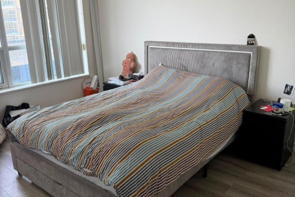 King size bed with striped duvet, nightstand, and laminate flooring - 811 - 2 Anndale Drive Toronto