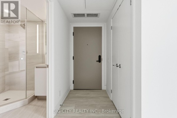 Apartment entryway with light wood floors, white walls, and a modern glass shower stall. - 811 - 25 Frederick Todd Way, Toronto