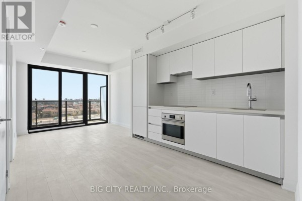 Open concept living space with white plank floors, white cabinets, and large balcony windows. - 811 - 25 Frederick Todd Way, Toronto