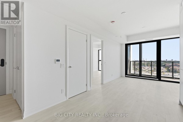 Bright living room with white floors, white walls, and panoramic city views from balcony doors. - 811 - 25 Frederick Todd Way, Toronto