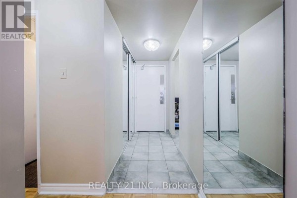 Hallway with tiled floor, mirrored walls, and a white door with frosted glass. - 811 - 25 Sunrise Avenue S, Toronto