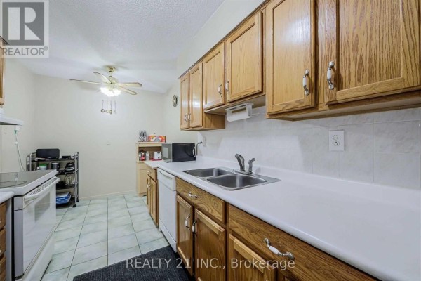 Kitchen corner with wooden cabinets, microwave, water bottles, and a small cabinet. - 811 - 25 Sunrise Avenue S, Toronto