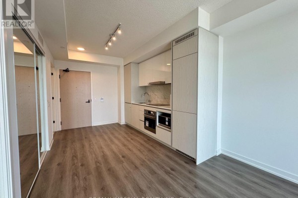 View of a studio apartment with mirrored closet doors and a compact kitchen. - 811 - 28 Interchange Way, Vaughan