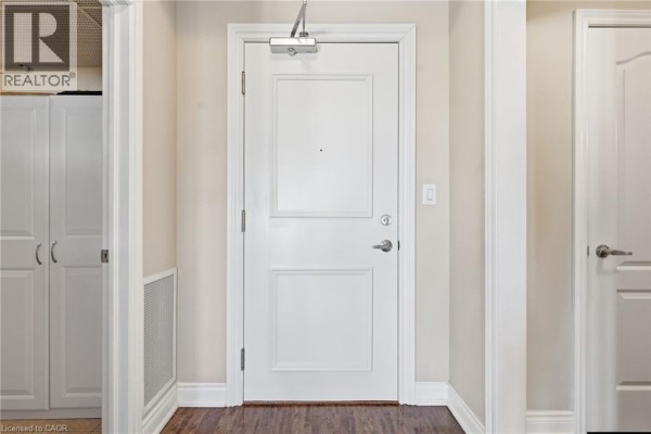 Interior hallway with a white apartment door, white closet, and beige walls. - 8111 Forest Glen Drive Unit# 521, Niagara Falls