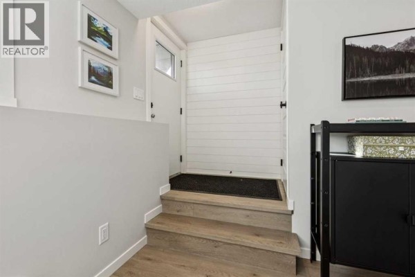 Interior entryway with light wood laminate flooring, white shiplap accent wall, and stairs. - 812, 135 Mahognay Parade Se, Calgary