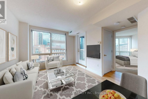 Living room with light wood floors, beige sofa, white armchair, and large window. - 812 - 100 Hayden Street, Toronto