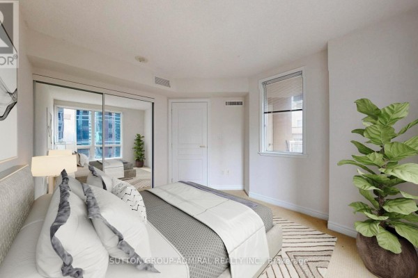 Bedroom with king-size bed, mirrored closet doors, and a large plant. - 812 - 100 Hayden Street, Toronto