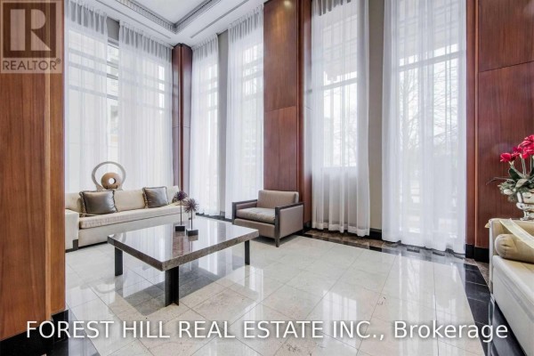 Elegant lobby with marble floors, wood paneling, large windows, and a seating area with a sofa. - 812 - 628 Fleet Street S, Toronto