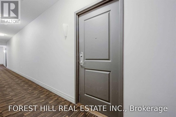A closed grey apartment door in a hallway with light grey walls and a patterned floor. - 812 - 628 Fleet Street S, Toronto