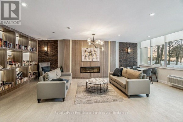 Common room with sofas, fireplace, coffee table, built-in bookshelves, and dining area. - 812 - 966 Inverhouse Drive, Mississauga