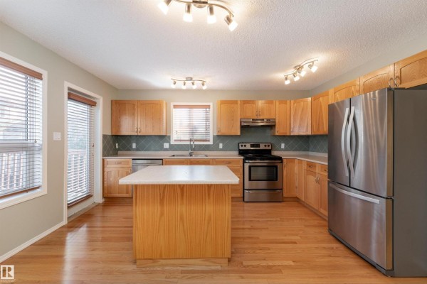 Kitchen with light wood cabinets, stainless steel appliances, and a center island. - 812 Barnes Link Sw, Edmonton
